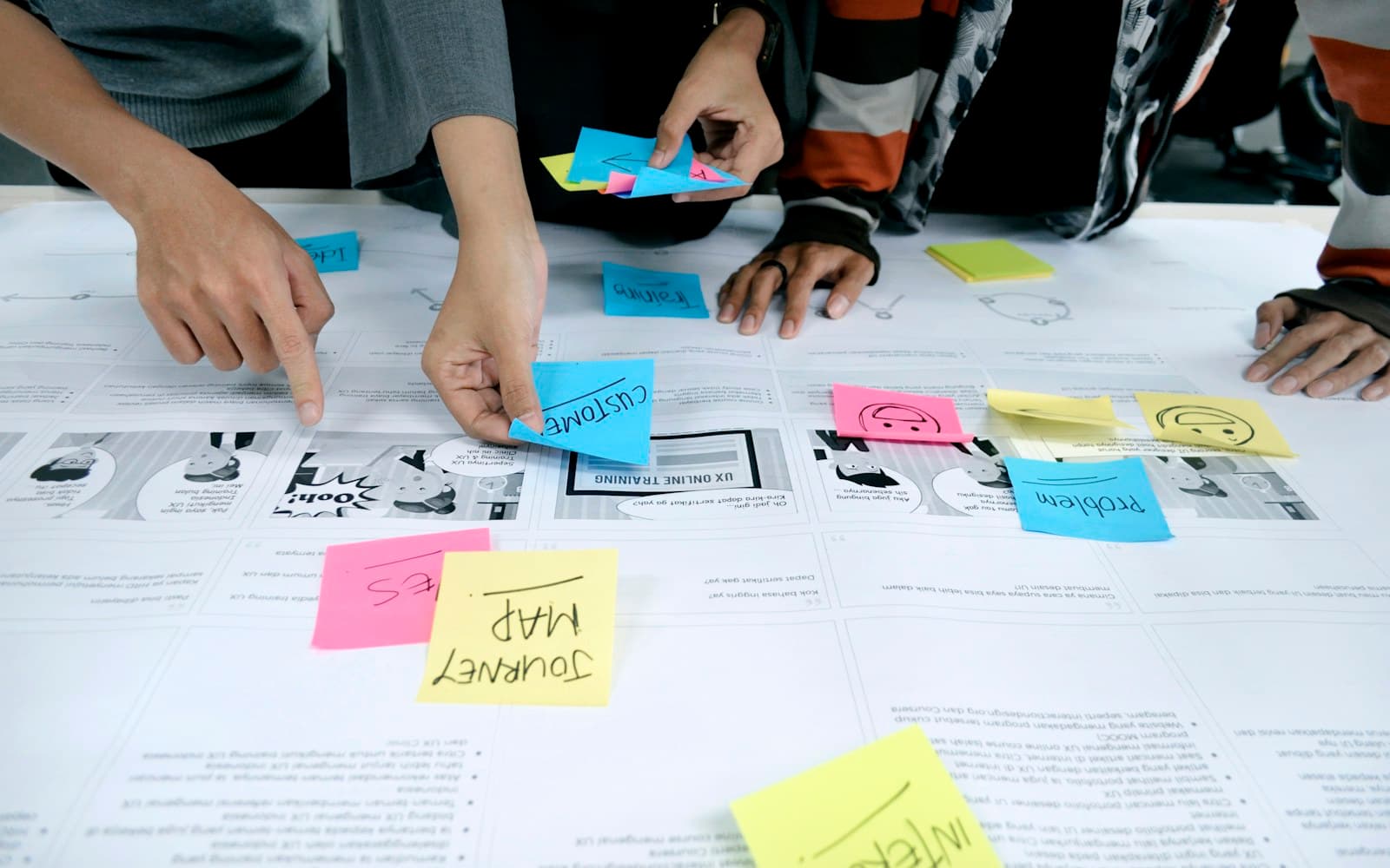 Hands arranging coloured sticky notes on a user journey map
