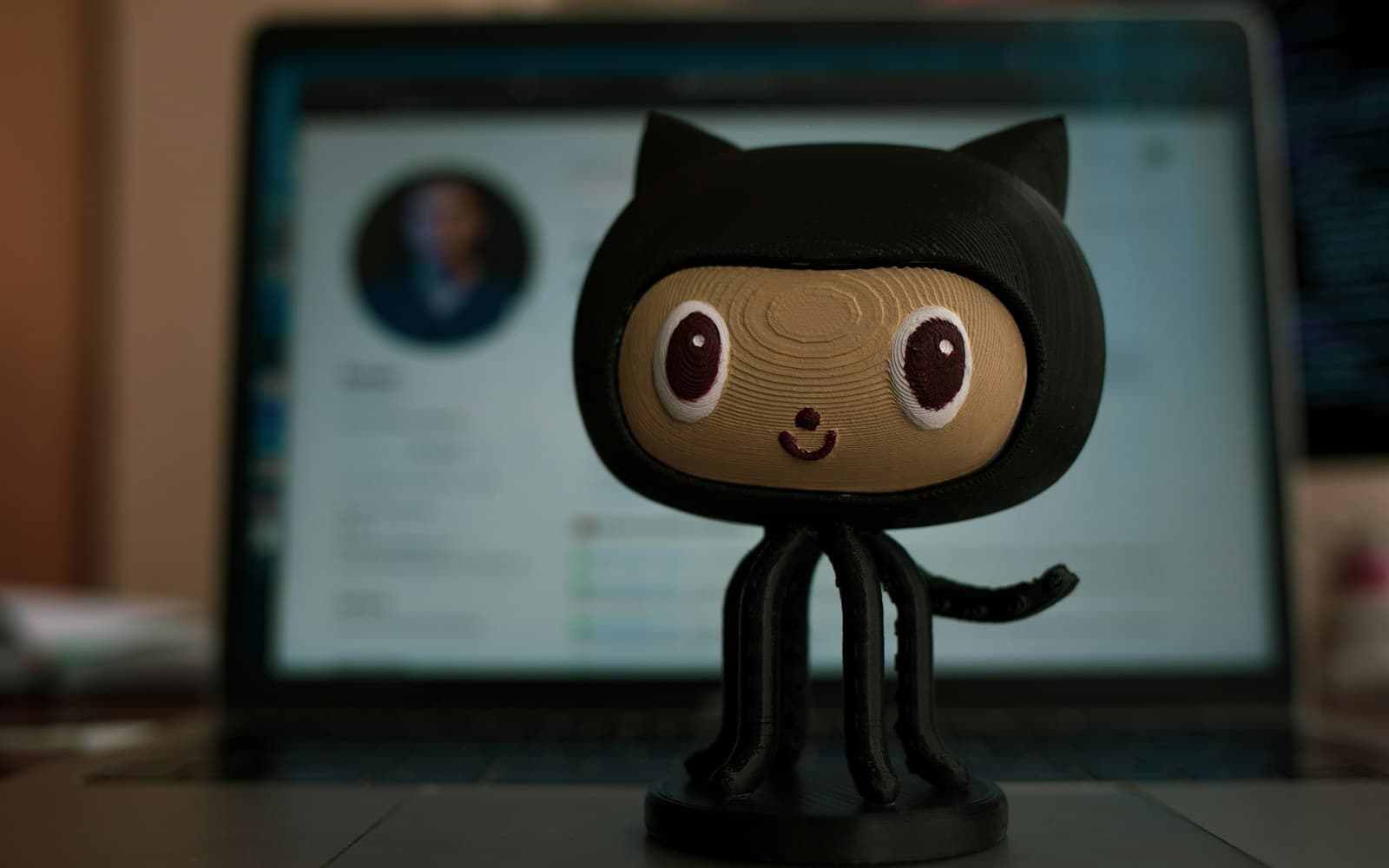 A GitHub Octocat figurine in front of a screen showing a repository